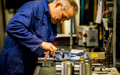 Hand de-burring parts at workbench by the machine, can't beat the human touch.